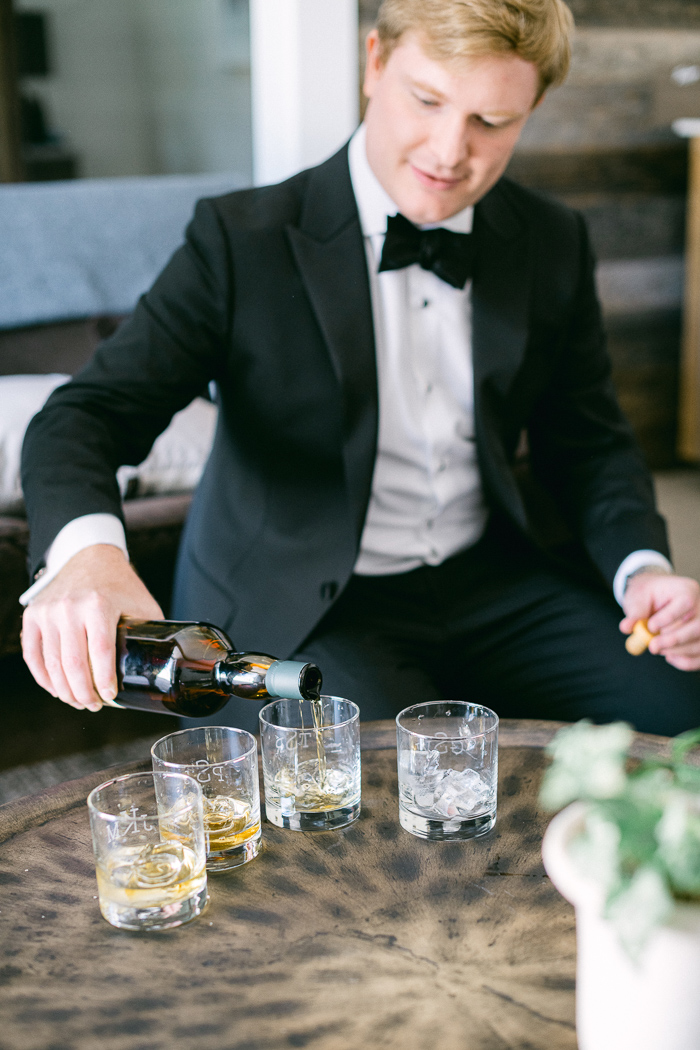 Groom pours scotch for groomsmen before wedding