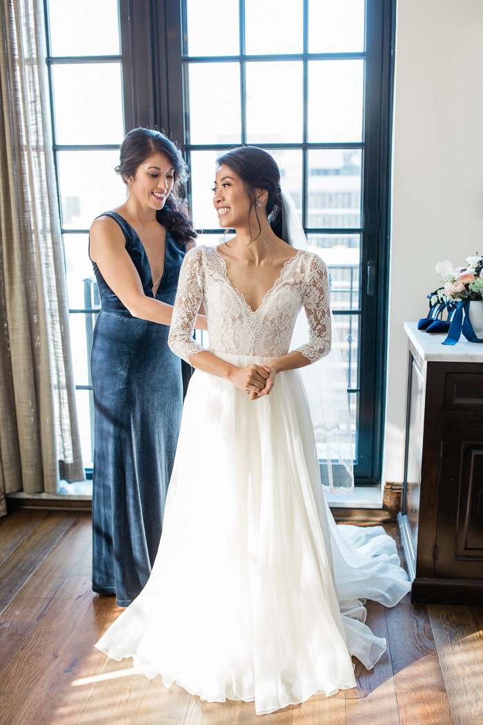 bride helping sister into her wedding dress