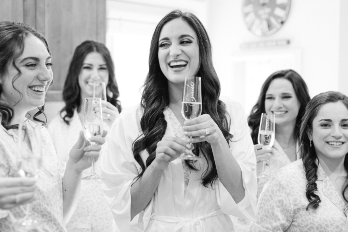 bride getting ready with champagne with wedding party