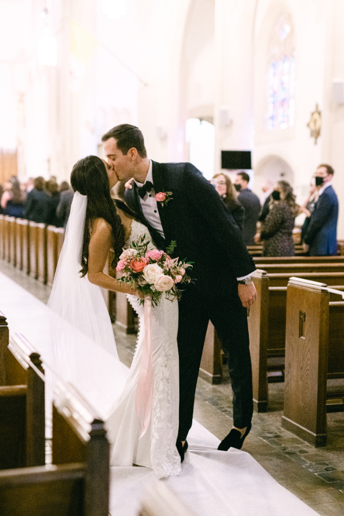 Bride and groom first kiss at the end of wedding recessional