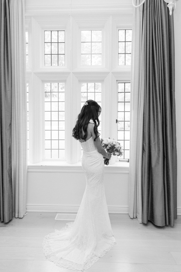 bride standing in window with bouquet
