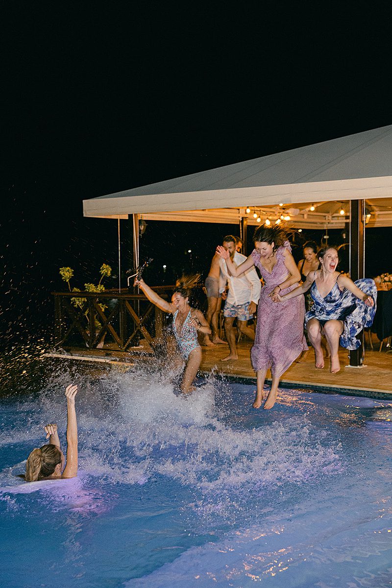 WEDDING GUESTS JUMPING IN THE POOL AT WEDDING RECEPTION AT ADMIRALS INN IN ANTIGUA