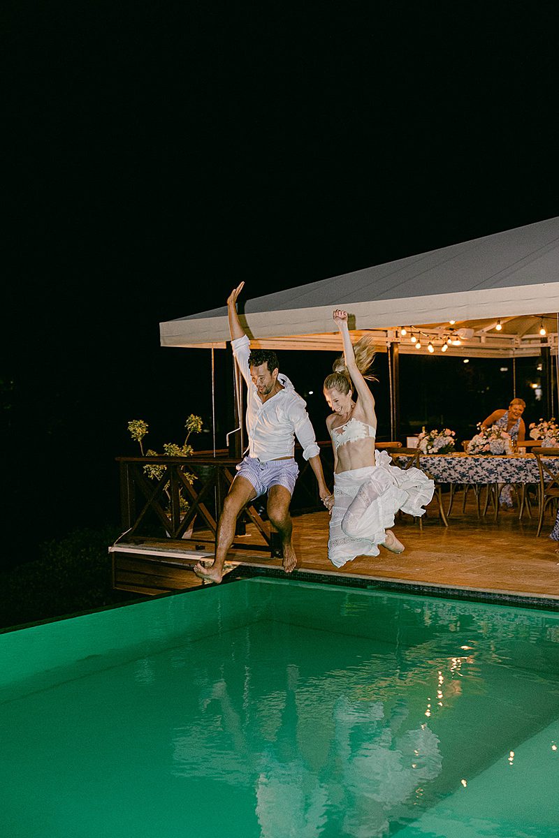 BRIDE AND GROOM JUMPING INTO POOL AT WEDDING RECEPTION AT ADMIRALS INN IN ANTIGUA